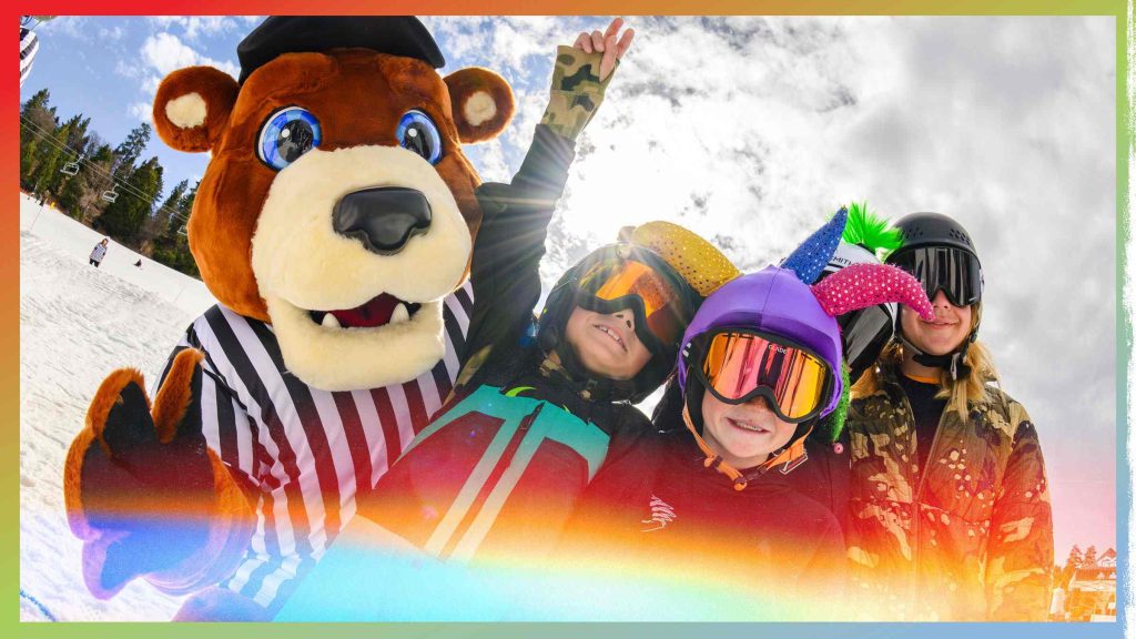 Big Bear Mountain ski mascot posing with skiers on a snowy mountain slope