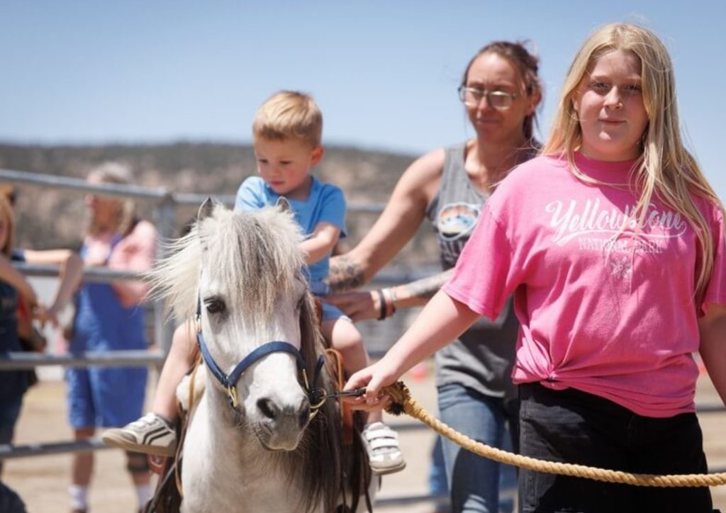 Child enjoying a pony ride with family assistance at Starlight Equestrian Ranch.
