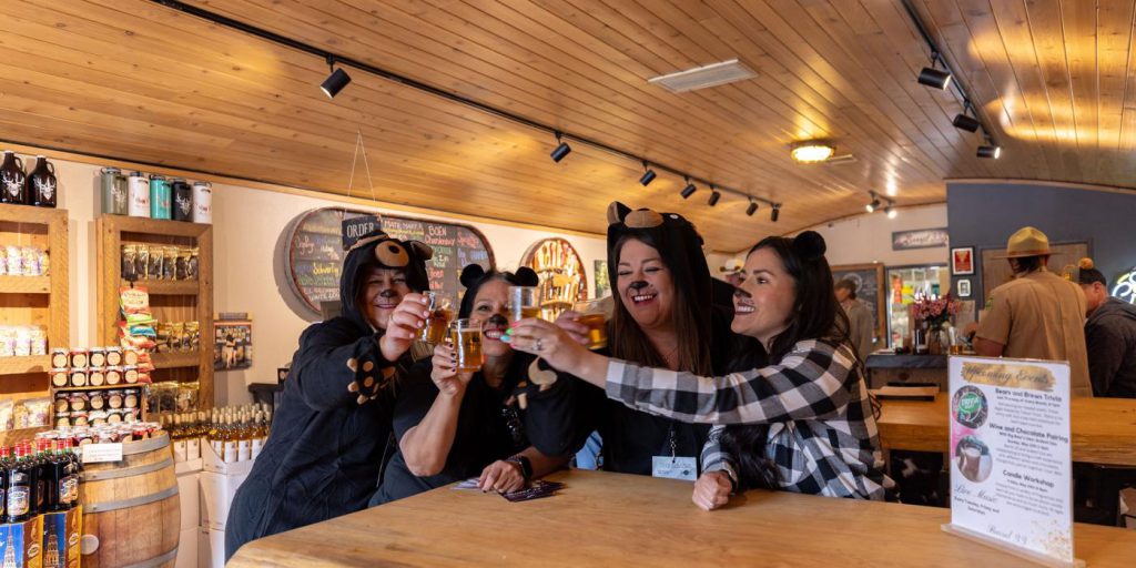 Three women wearing cat ears cheerfully toast with beers at the Bear Crawl Big Bear event.