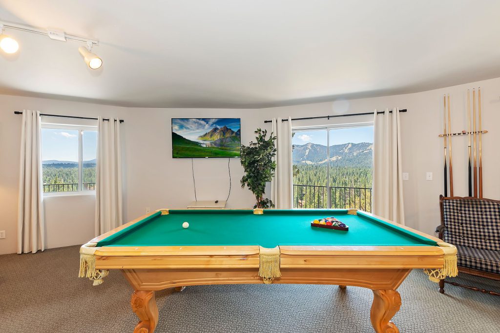 A Big Bear game room with a billiards table and large windows offering a scenic view of the mountains.