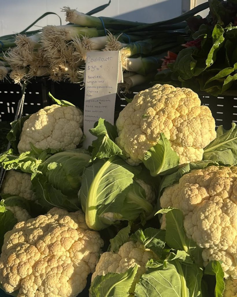 A close-up display of fresh cauliflower and leeks at the Farmers Market in Big Bear.
