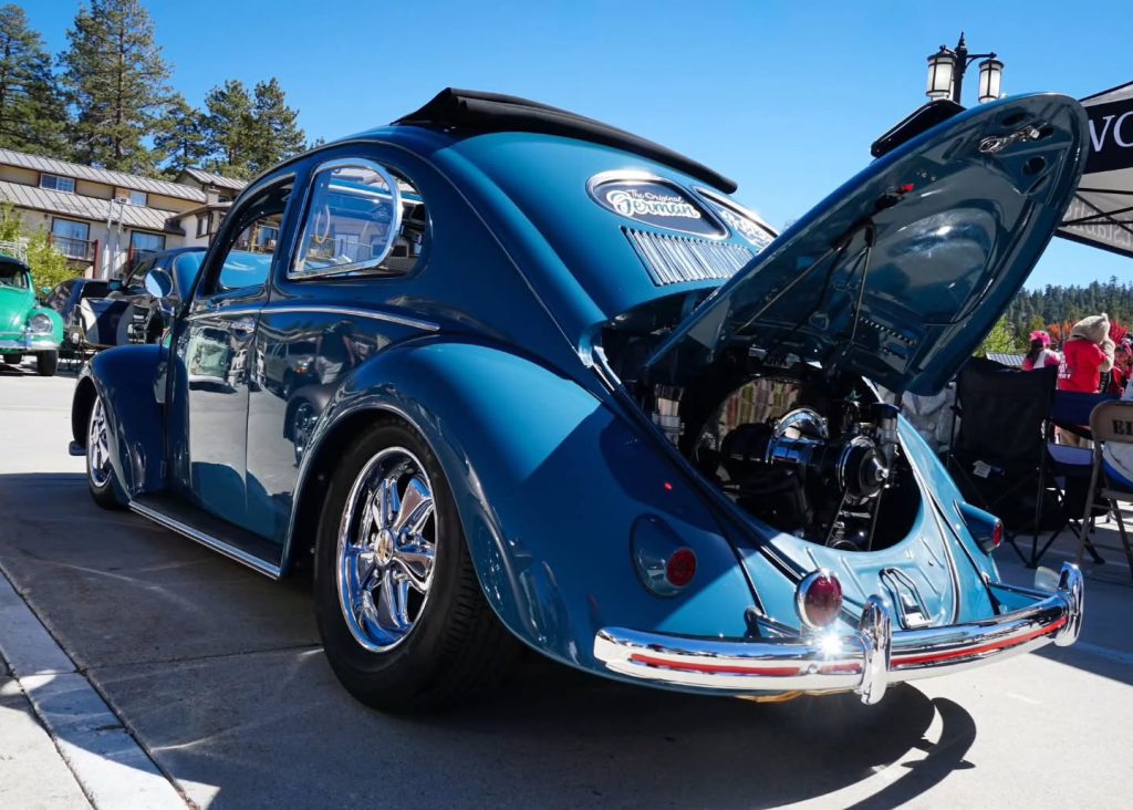Close-up view of a restored blue classic Volkswagen Beetle with an open hood and custom details