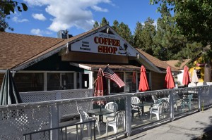 The exterior of a restaurant called Azteca Grill is shown on a sunny day in Big Bear, with green trees and a blue, cloudy sky in the background.
