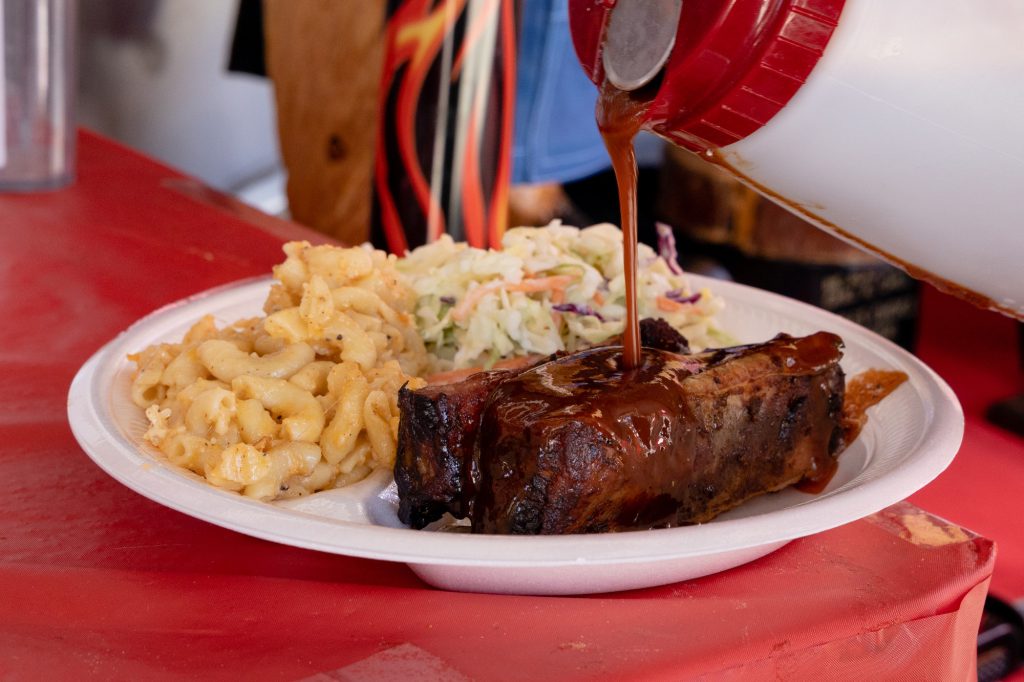 BBQ ribs topped with sauce served with macaroni and coleslaw at a barbecue competition.