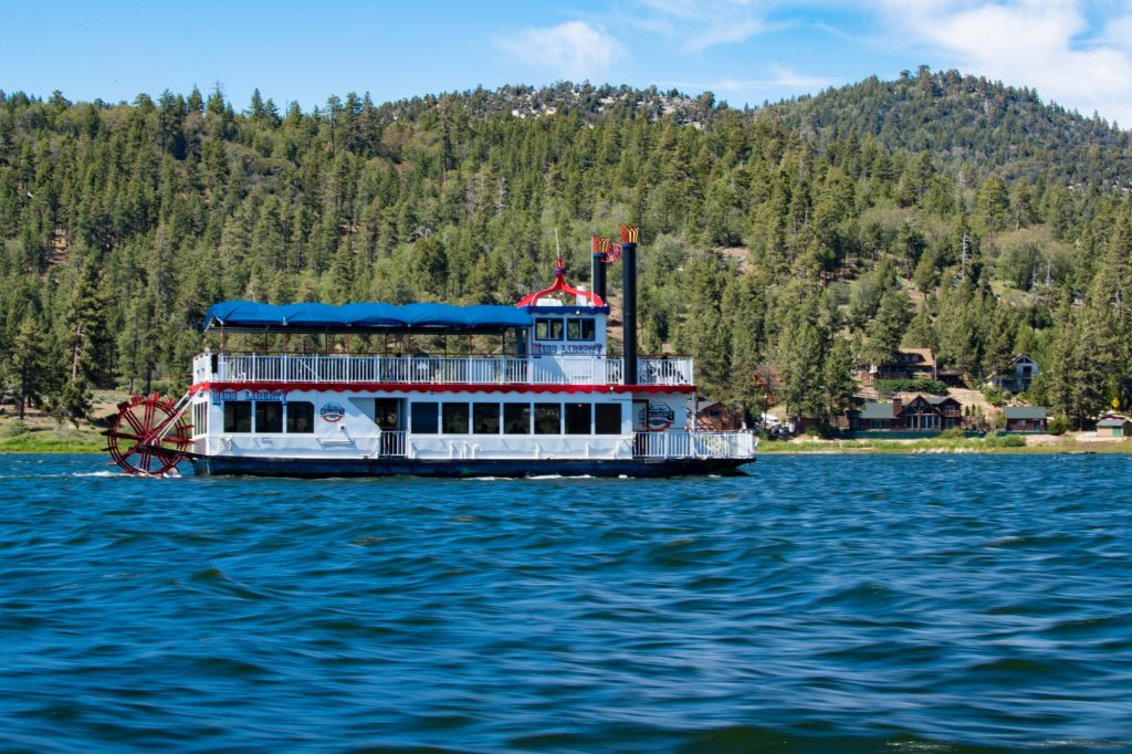 Paddle boat cruising on Big Bear Lake with mountain forest and lakeside cabins in the background