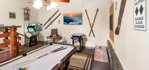 Game room at a Bear Escapes cabin featuring a pool table, arcade games, and mountain-themed décor.