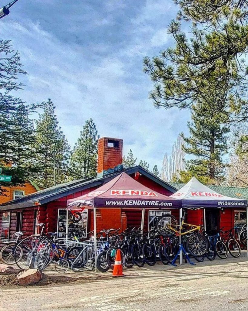 Exterior view of Bear Valley Bikes shop with multiple bicycles displayed outside and service tents in Big Bear.