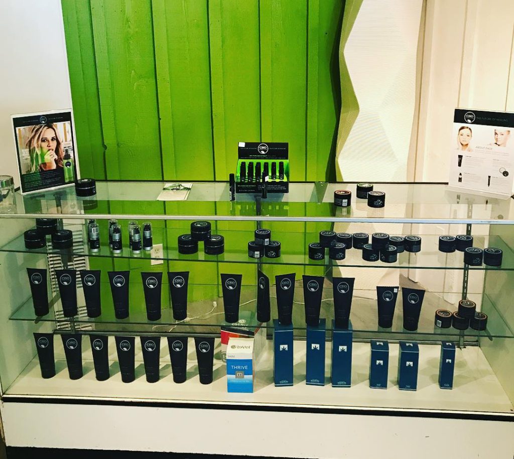 Glass display case filled with CBD and wellness products at Bear Valley Wellness Center, neatly arranged with a green wall background.