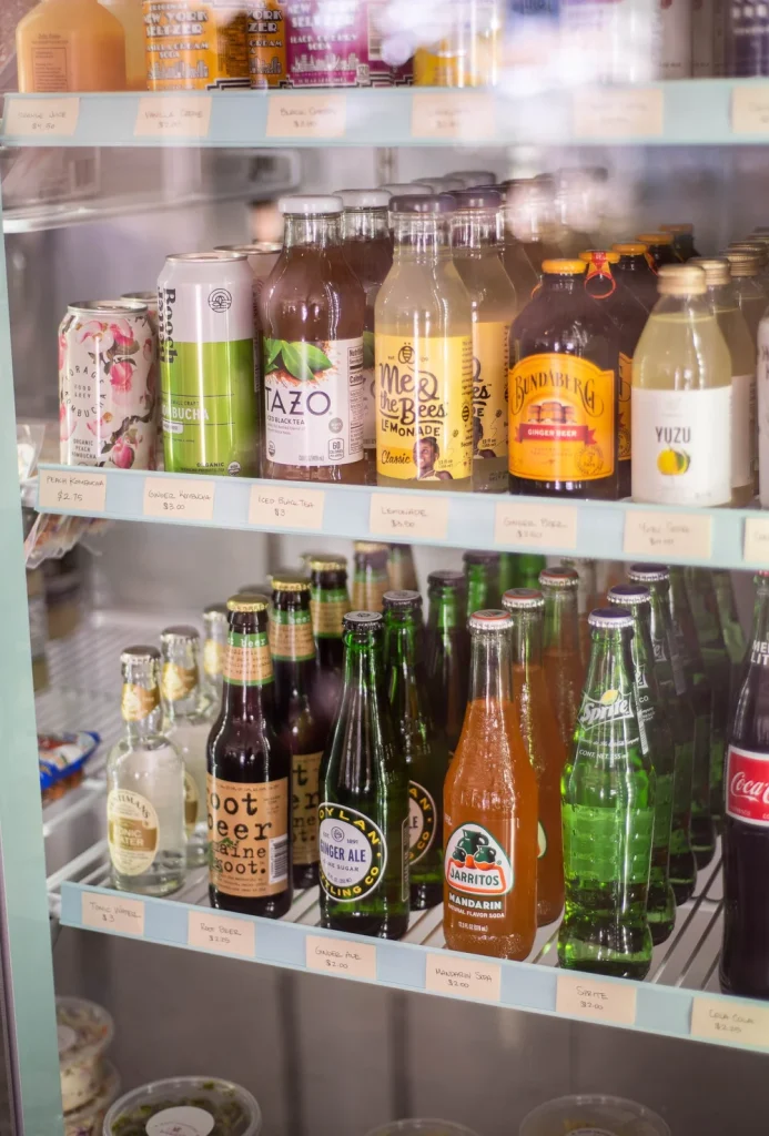 A shelf at Bear Cupboards Market displaying a variety of chilled beverages and assorted items in Big Bear.