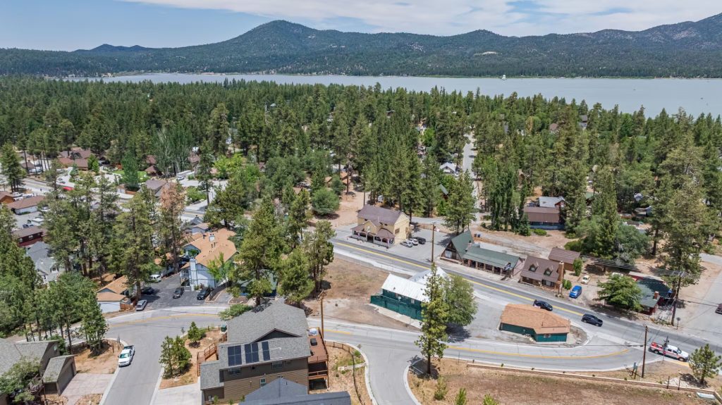 Aerial view of Big Bear City with pine forests, mountain landscape, lake, and residential area.