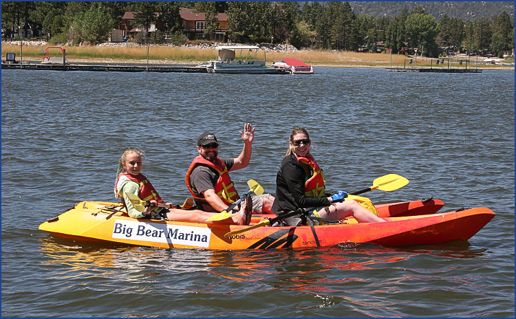 Family kayaking on Big Bear Lake with colorful tandem kayak near marina on a sunny summer day