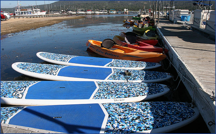 Paddle boards and kayaks lined up at the dock at Big Bear Marina with scenic lake and marina waterfront view
