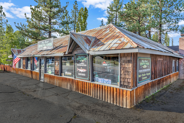 Historic exterior of Big Bear Sporting Goods store featuring a rustic mountain-style building, outdoor sporting equipment signage, and tall pine trees.