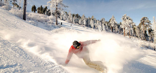 Snowboarding turning in a blue ski day on a snow covered mountain
