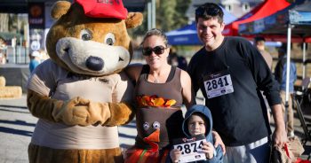 A family posing for a photo with a Big Bear mascot at the Turkey Trot race