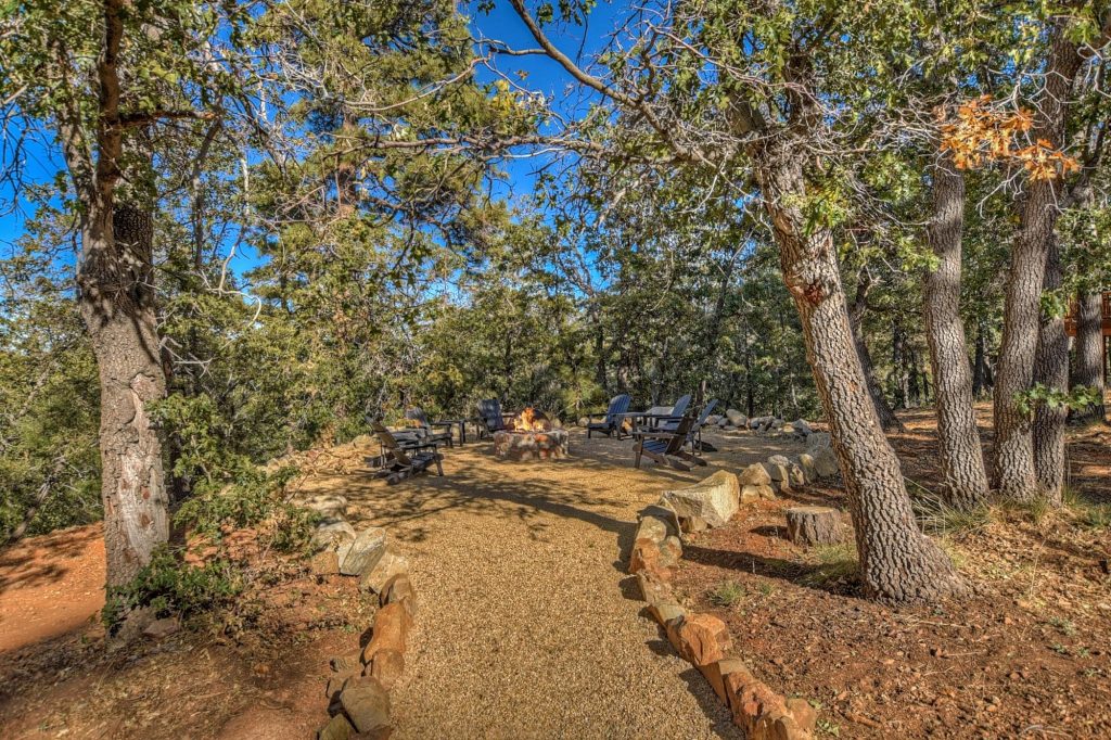Scenic pathway leading to the outdoor firepit area at Big Sky cabin surrounded by trees.