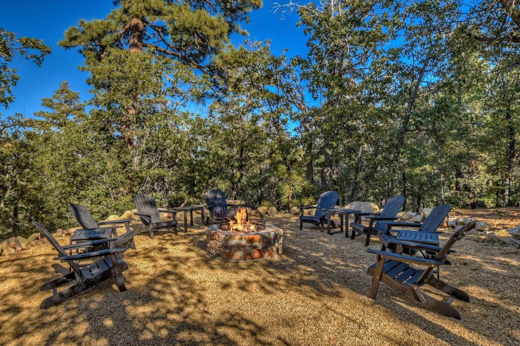 Forest-side firepit lounge area at Big Sky cabin with cozy outdoor seating and natural surroundings.