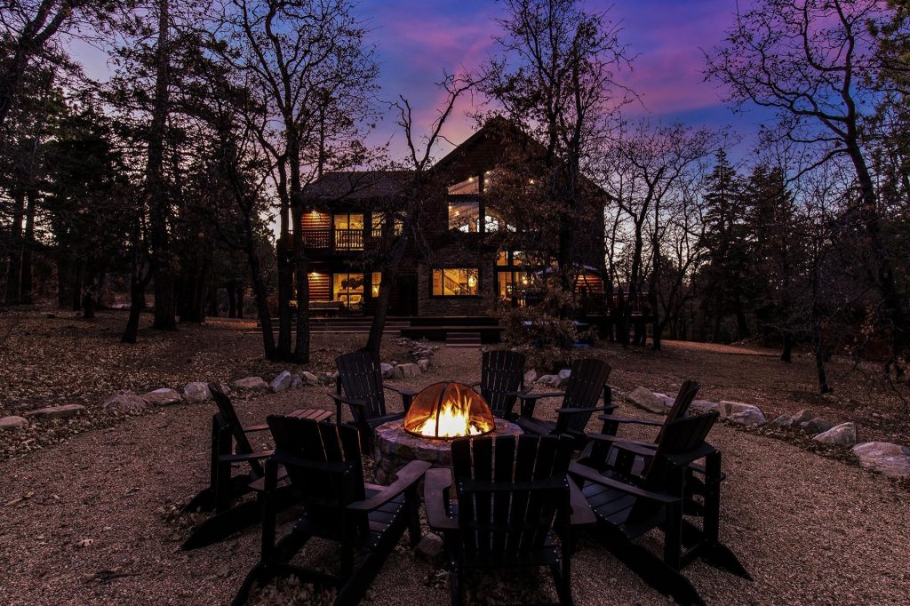 Evening firepit retreat at Big Sky cabin with Adirondack chairs under a colorful mountain sky.