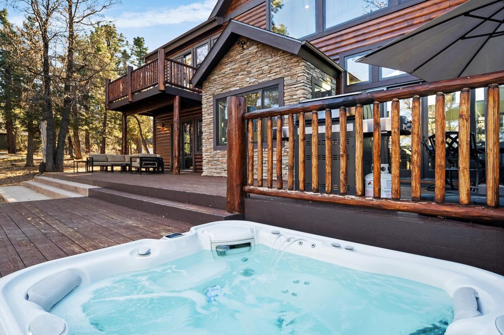 Luxury outdoor hot tub at Big Sky cabin surrounded by forest and spacious wood deck.