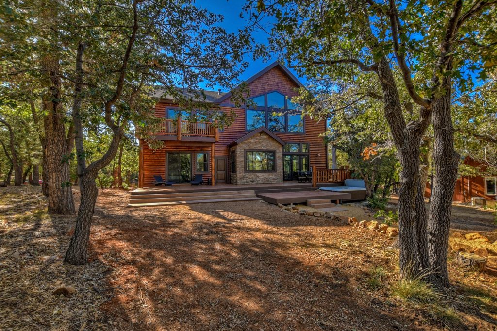 Mountain cabin exterior surrounded by mature trees with a spacious outdoor deck