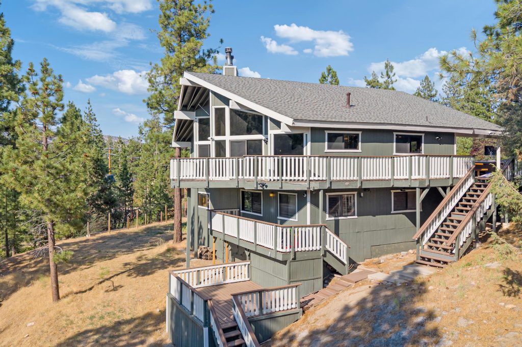 Multi-level cabin exterior with wraparound decks surrounded by pine trees