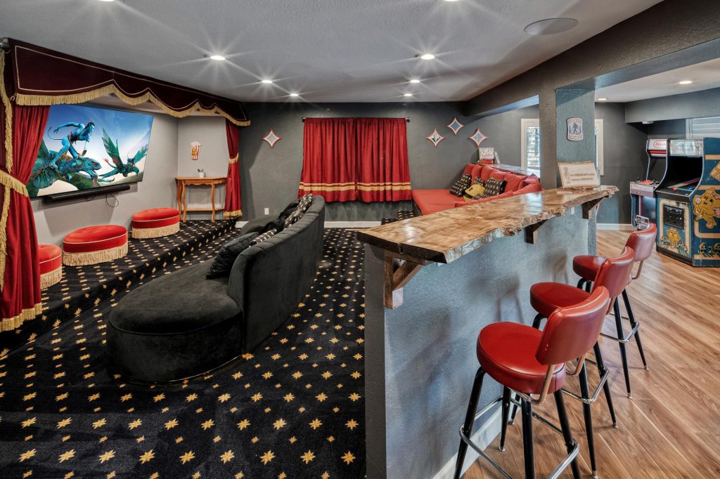 Home theater and game room with movie seating, bar stools, and arcade machines