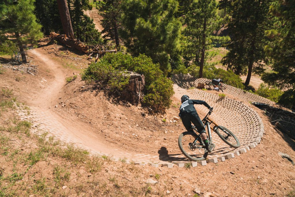 A mountain biker rides down a curved dirt trail at Big Bear.