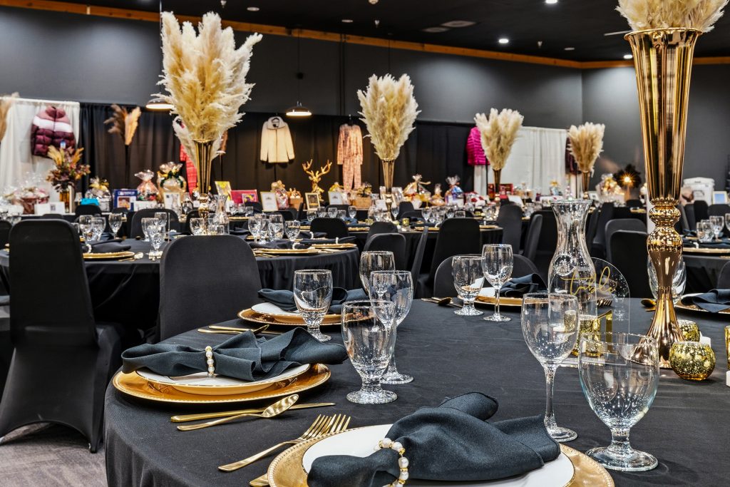 Dining table arrangement in banquet hall with elegant black and gold theme