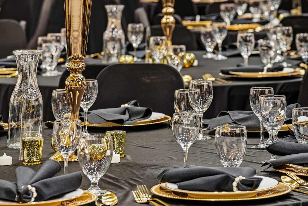 Decorated banquet hall with multiple round tables and pampas grass centerpieces