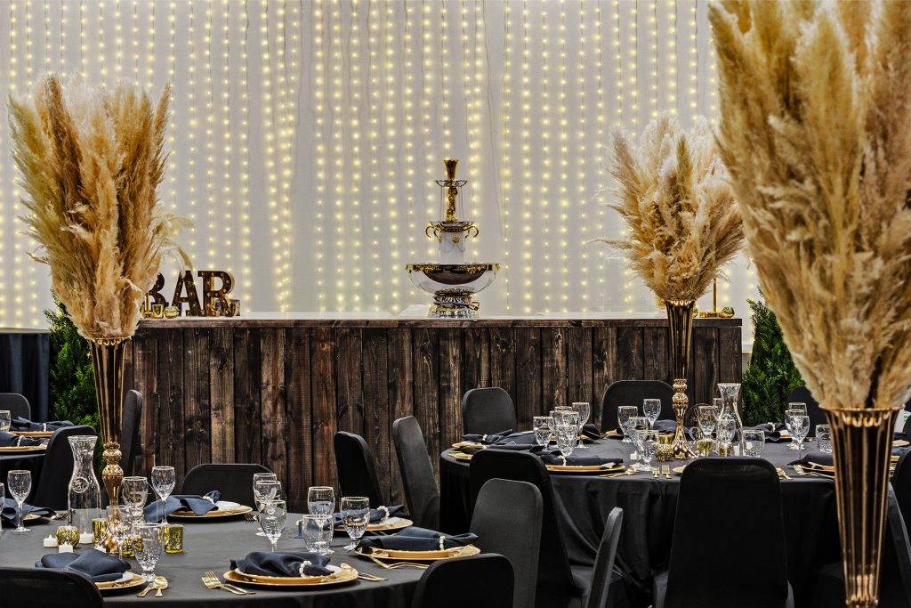 Bar counter with warm lighting, pampas grass decor, and rustic wooden finish