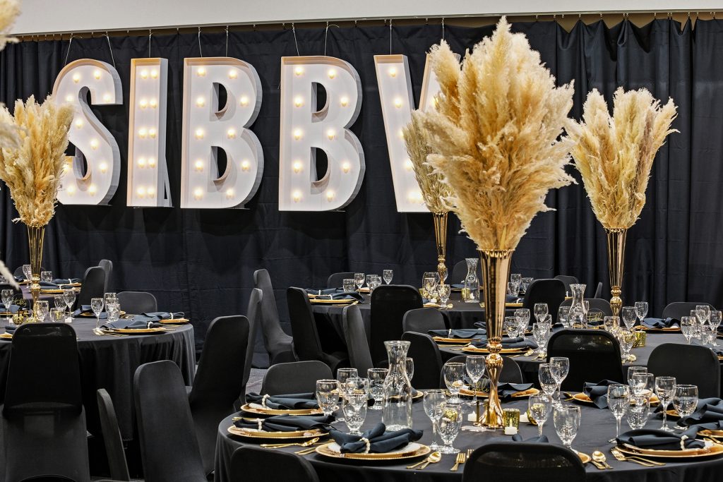 Event hall with large SIBBI illuminated sign and luxury table setup