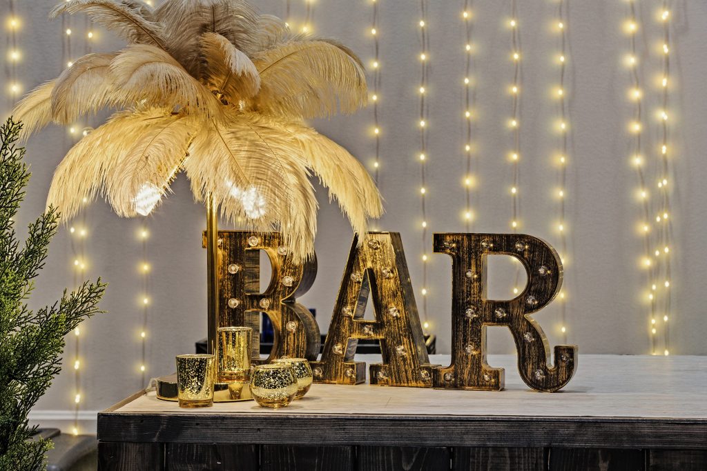 Close-up of illuminated BAR letters with feather lamp and decorative candles