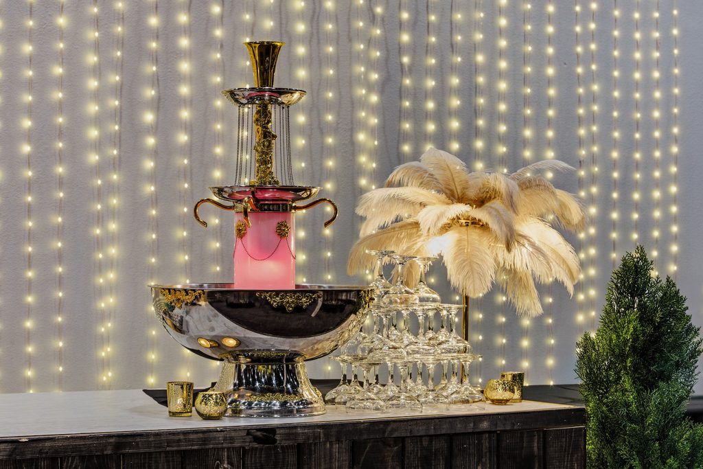 Luxury champagne fountain display with glasses, gold accents, and decorative lighting backdrop