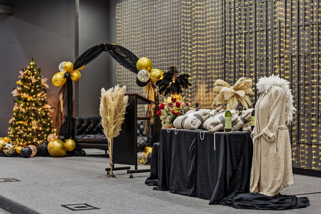 Wide view of banquet stage with balloon arch, lighting backdrop, and decorated tables