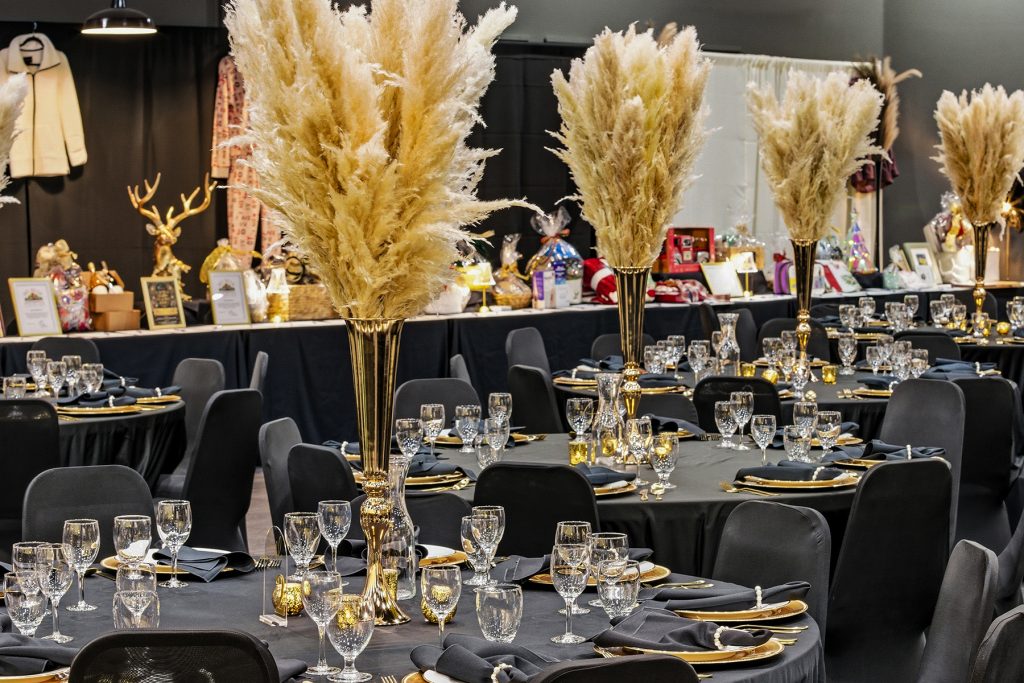 Banquet hall dining setup with black tablecloths, gold centerpieces, and elegant table arrangements