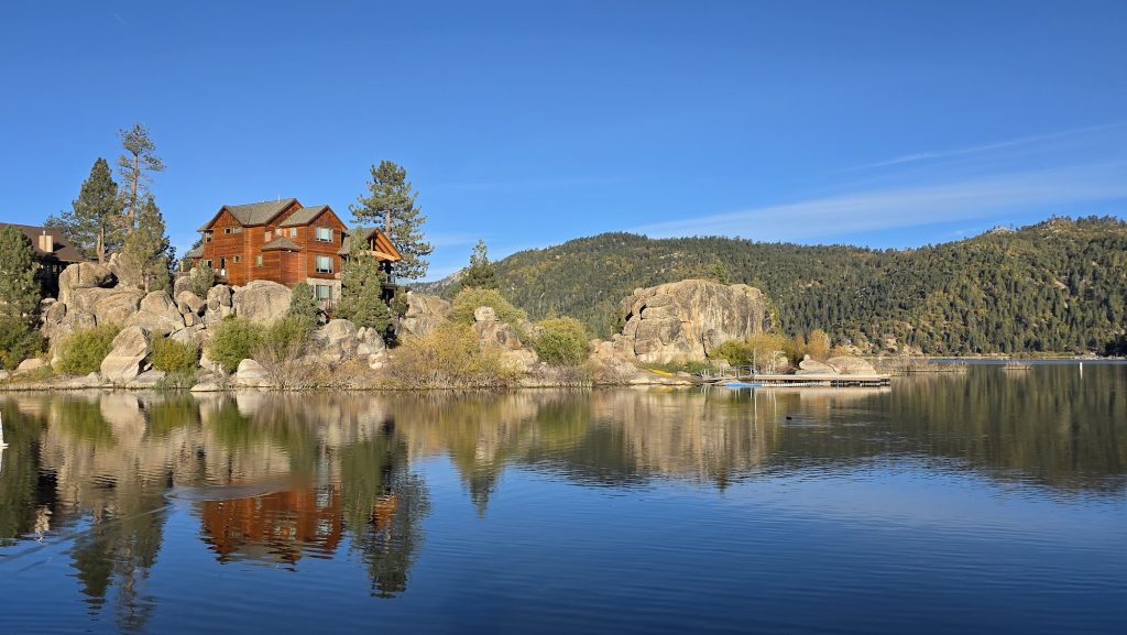 Panoramic view of Boulder Bay Park with granite boulders, pine trees, and lake reflections under a clear blue sky
