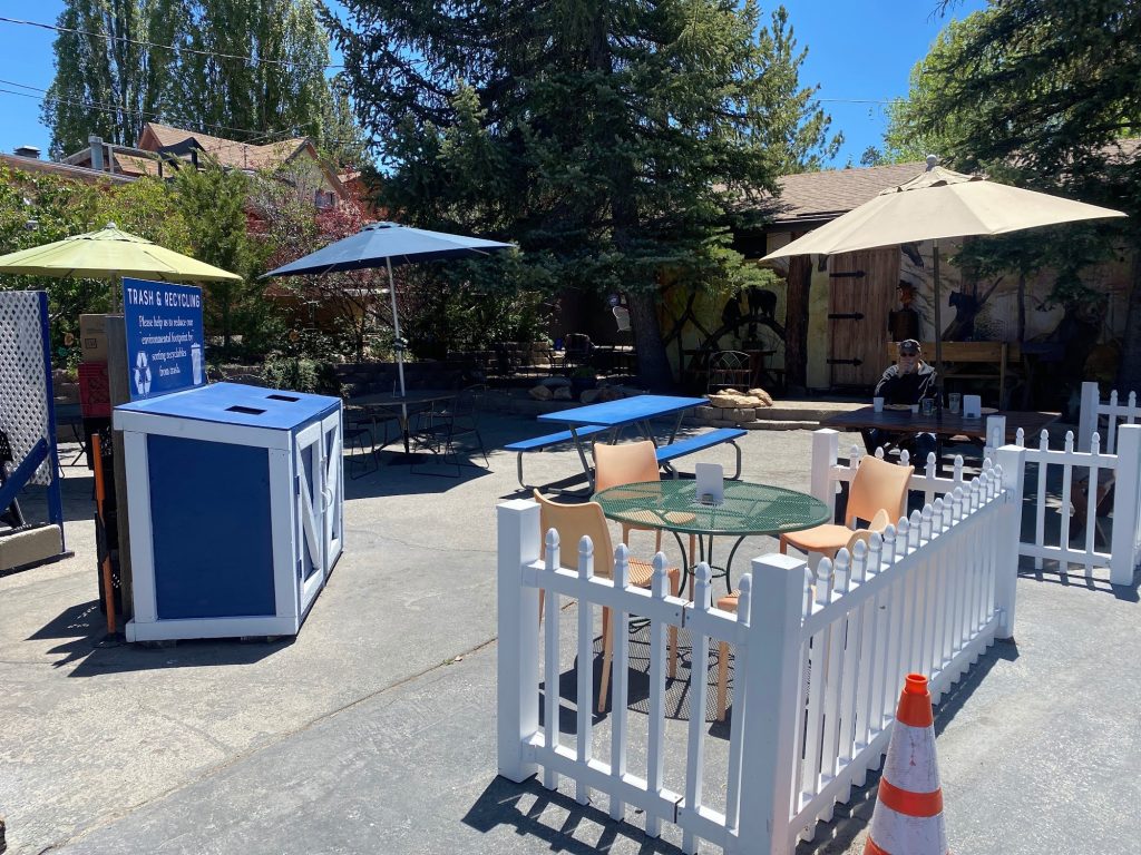 Outdoor seating area at Café Crêpe with tables, umbrellas, and a white picket fence.