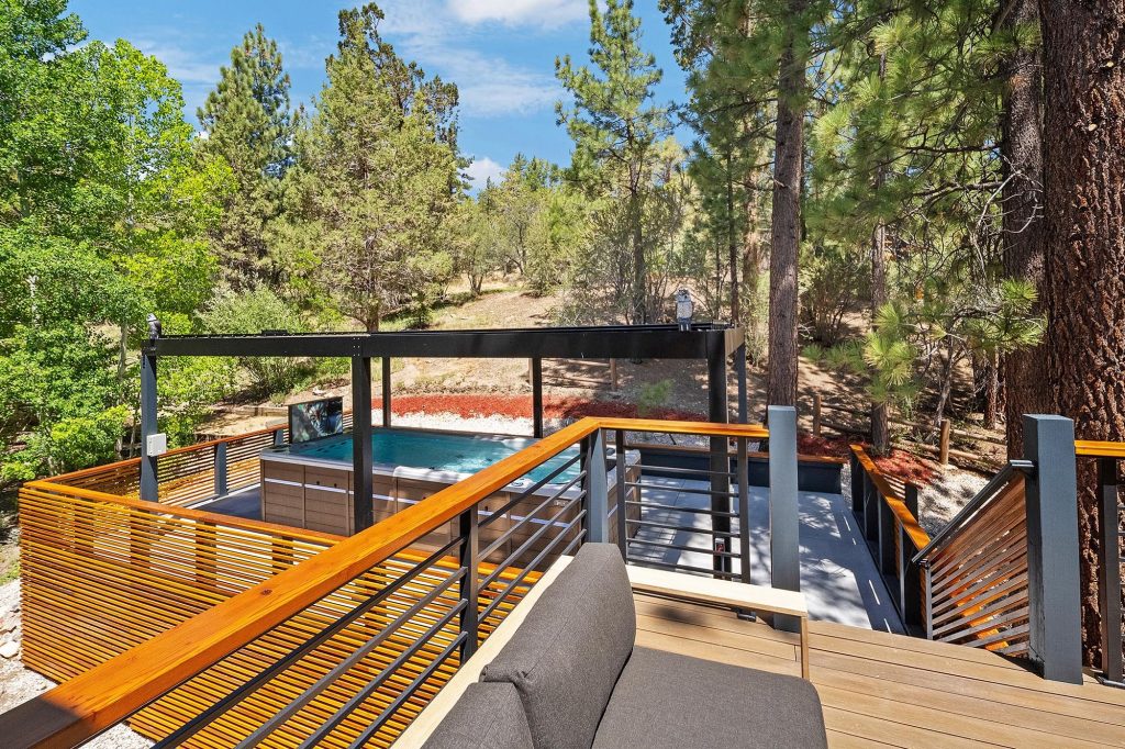 Private swim spa patio at Castlewood Pines with wood railings, shaded pergola, and forest views.
