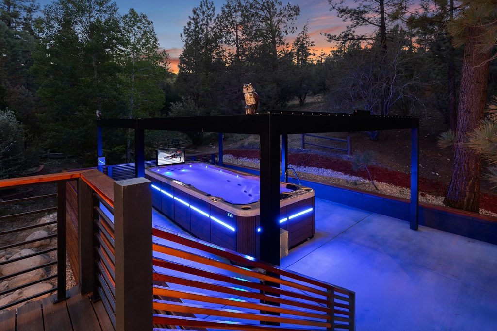 Evening view of the illuminated swim spa area at Castlewood Pines surrounded by pine trees.