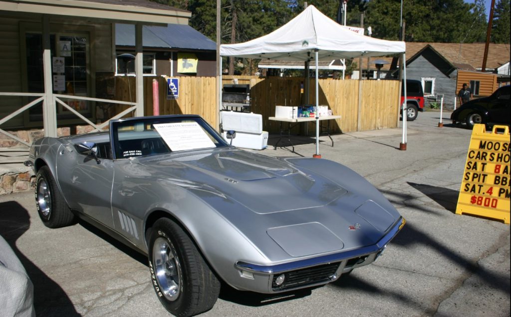 A classic silver Corvette convertible is parked at a car show in Big Bear.