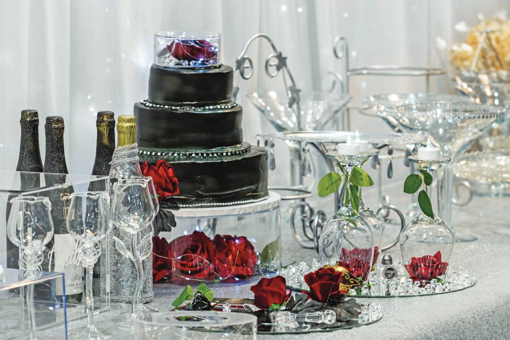 Black-themed birthday cake, wine bottles, and crystal decorations on a celebratory table.