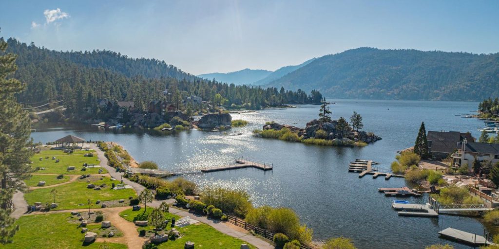 Aerial view of Boulder Bay Park in Big Bear featuring landscaped walking paths, docks, granite boulders, and scenic lake and mountain views.