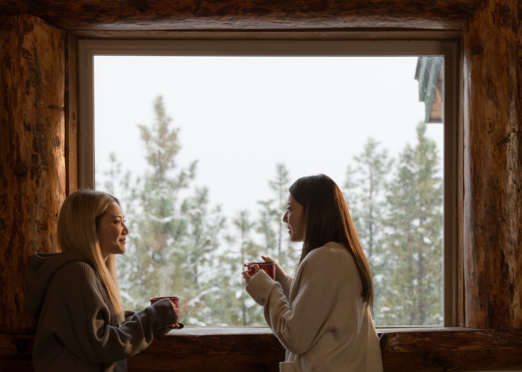 Couple enjoying a cozy moment by the window with a view of snow-covered trees in Big Bear.