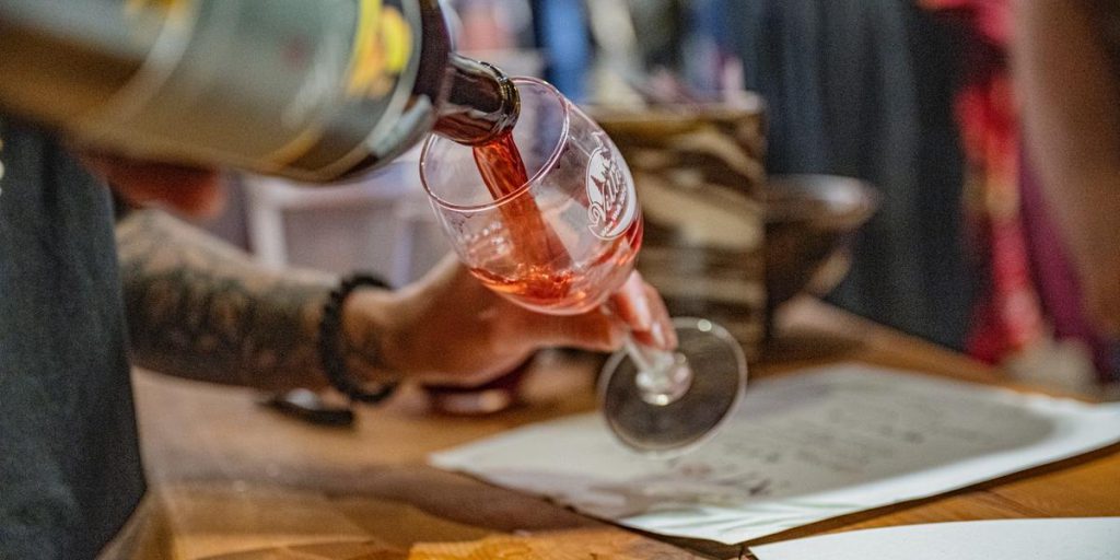 Pouring red wine into a glass during a wine tasting experience at a bar