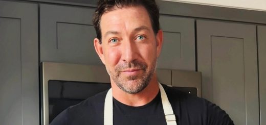 David Dawson, a chef in Big Bear, stands in front of a kitchen wearing a blue apron, ready to cook.