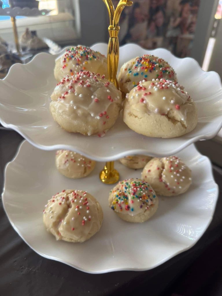 Homemade frosted sugar cookies with colorful sprinkles displayed by Mi Familia Cocina.
