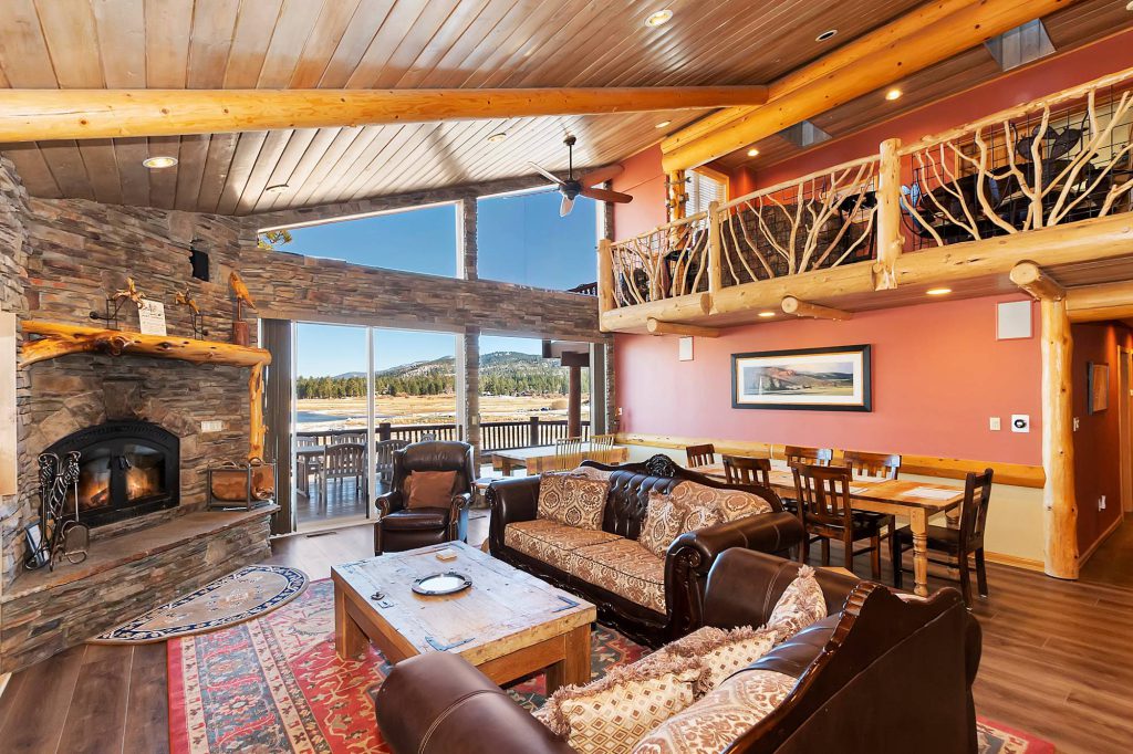 A woman and two children stand on a porch in front of the Grizzly Manor Cafe sign in Big Bear, with the woman holding a child's hand while the other child stands next to them.