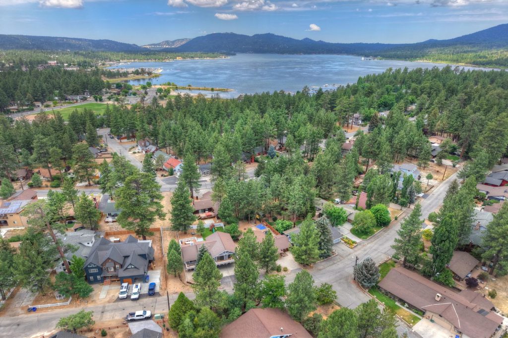 Aerial view of a lakeside Big Bear neighborhood surrounded by pine trees near Ski Beach