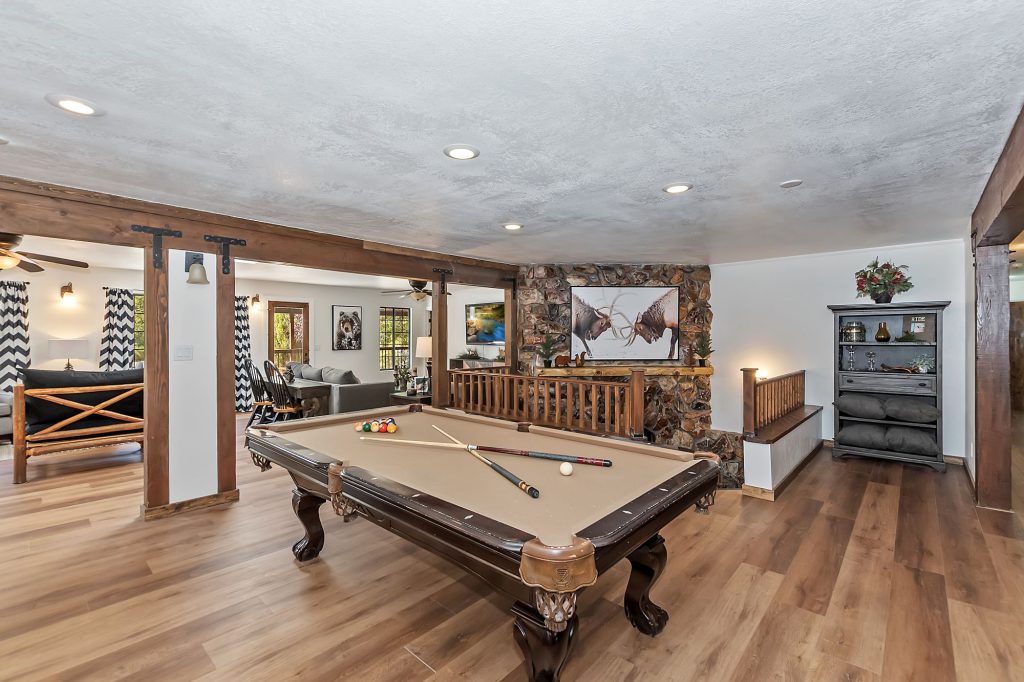 A Big Bear lodge with a billiards table and a living area with a stone fireplace.