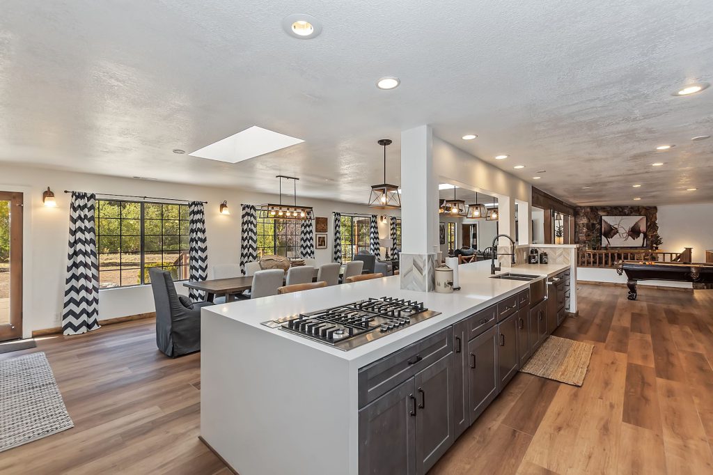 A modern kitchen in a Big Bear home with a large island cooktop and an open view to the dining and living areas.